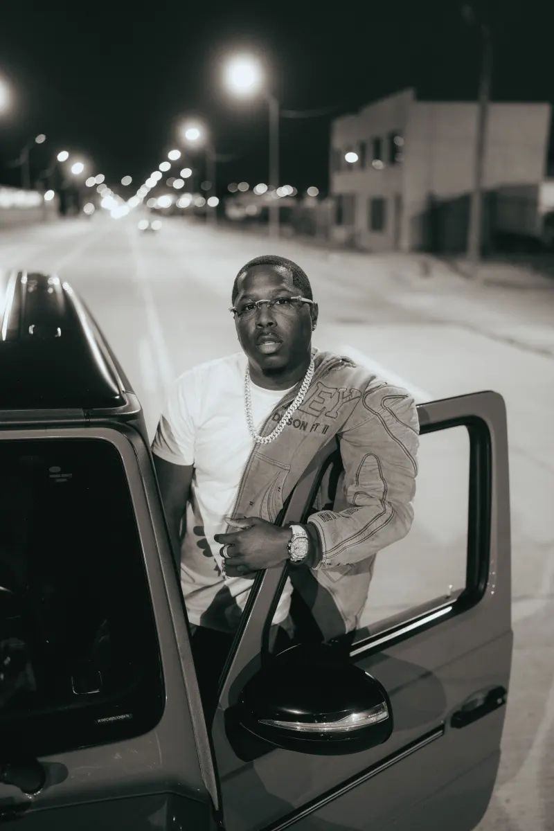 Coach Joey stepping out of a car on a city street at night, in black and white
