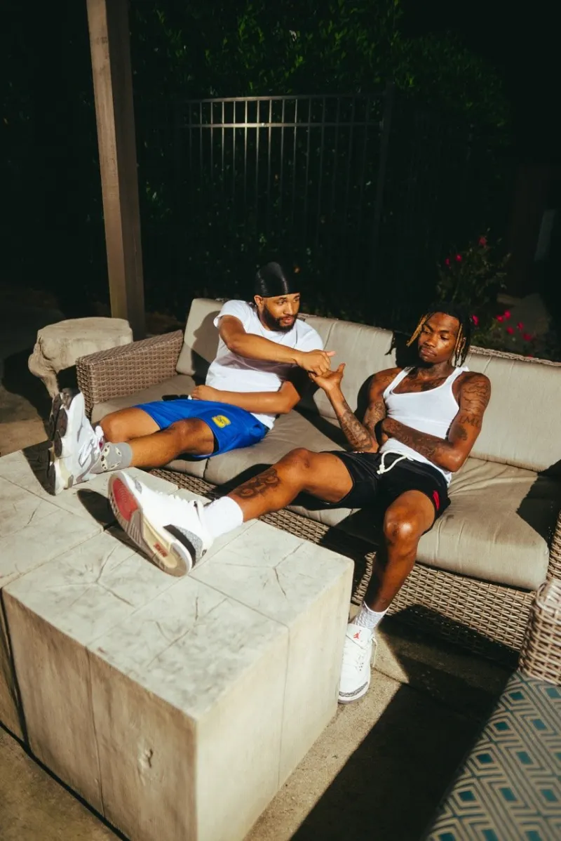 Two men in Missing in Silence pieces lounging on a concrete bench at night